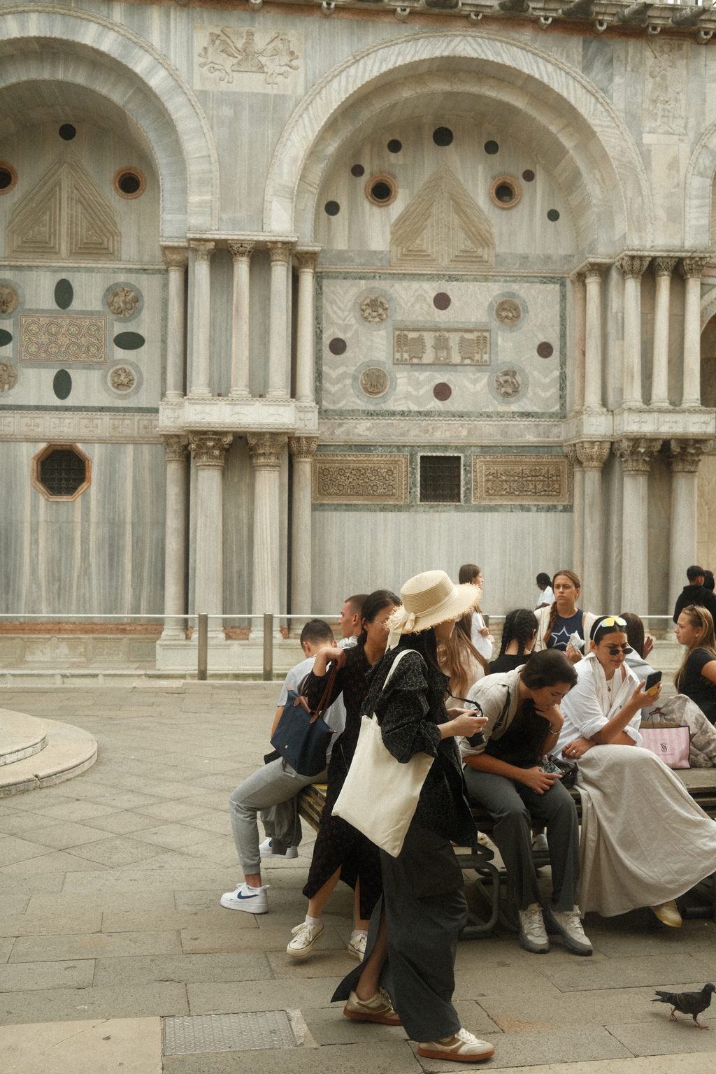 A group of tourists and a woman in a straw hat against the north face of the Basilica di San Marco