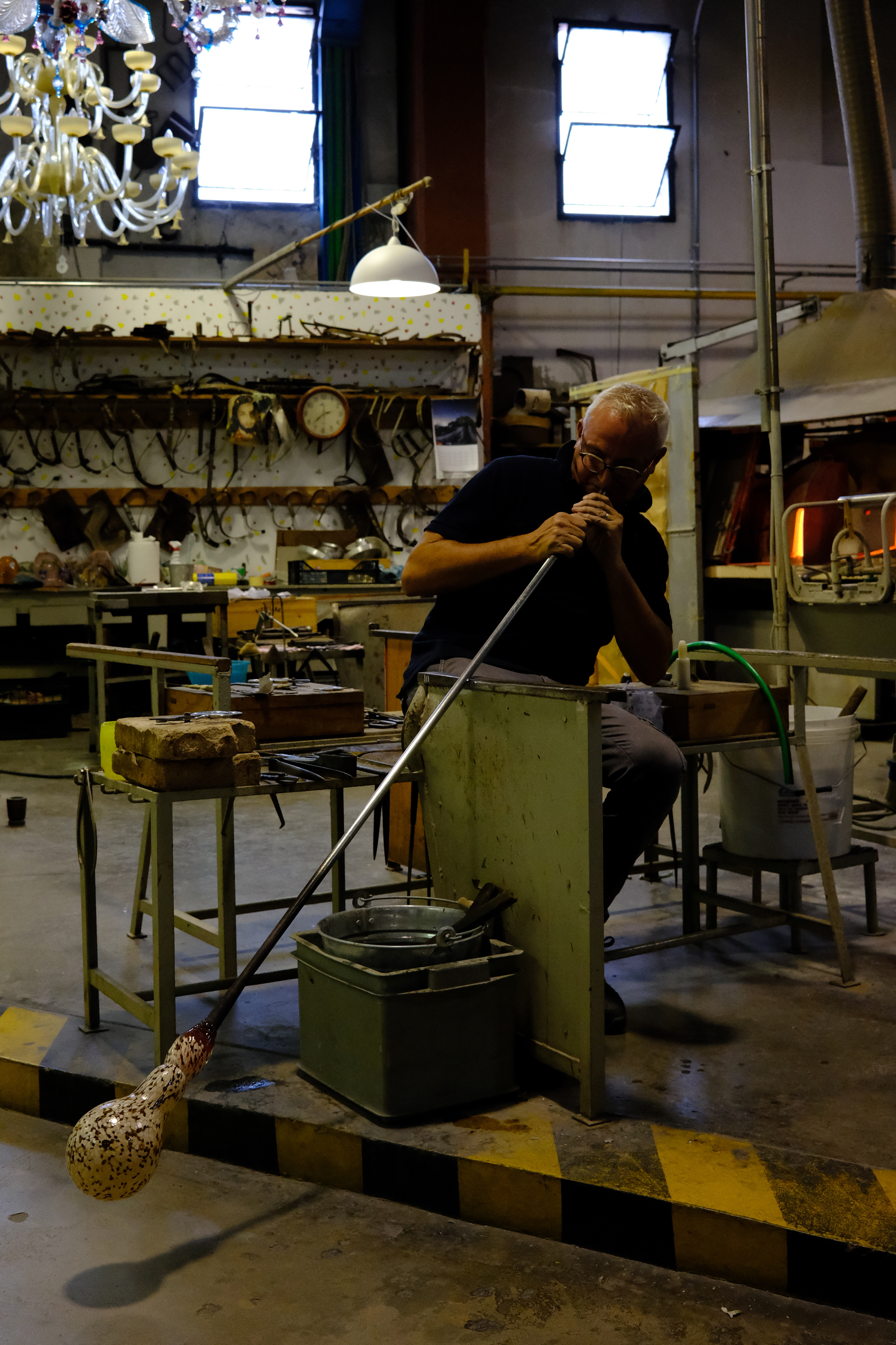 Glass blower, blowing to form a bulb to shape into a pitcher