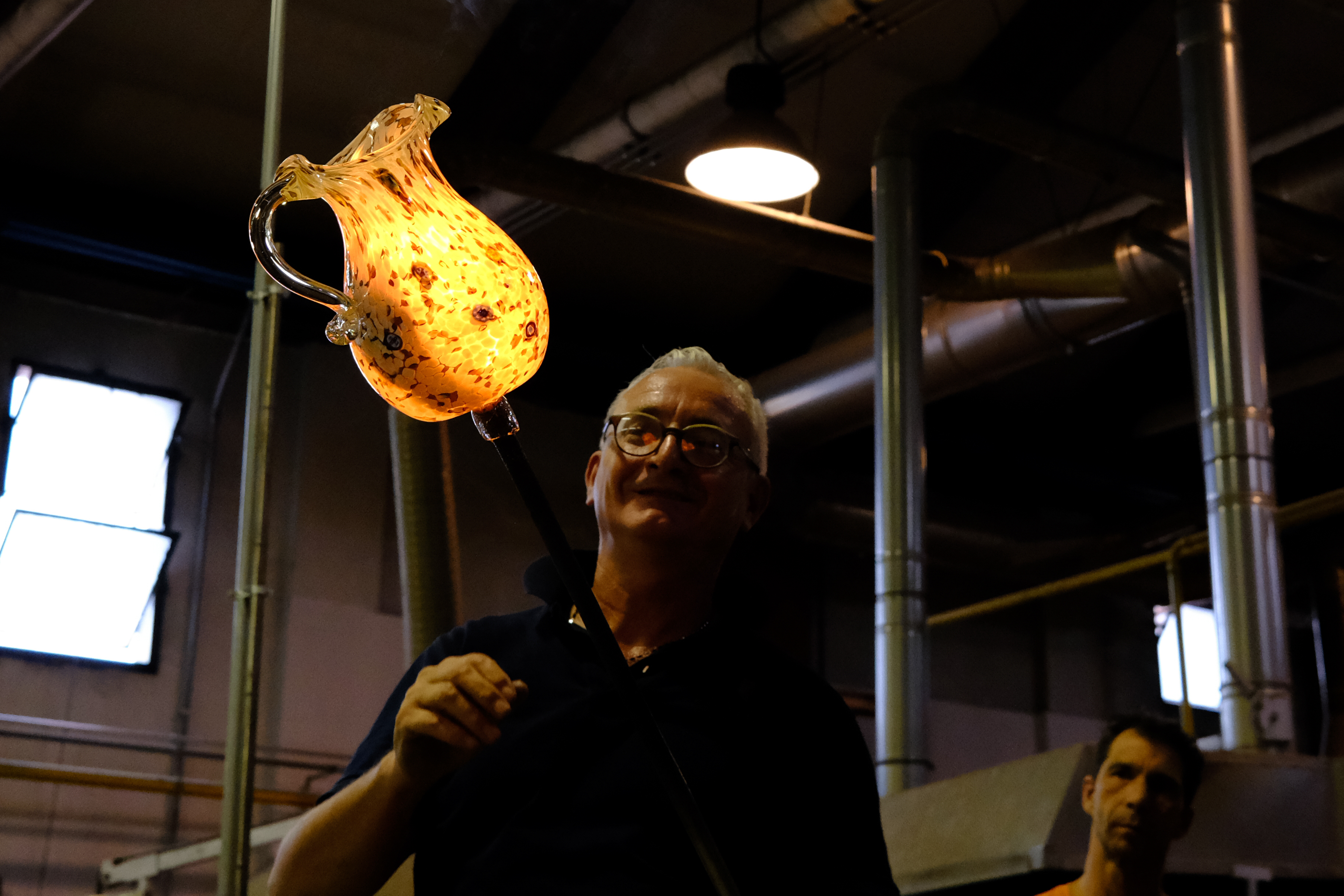 Glass blower placing flash paper inside of a just-completed pitcher