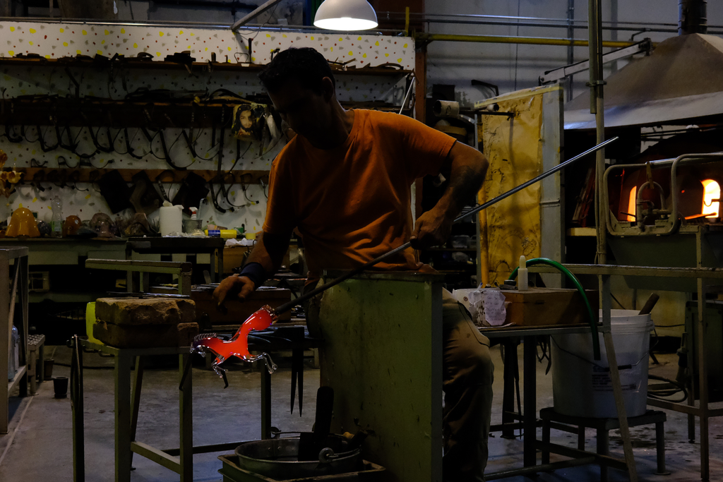 Glass blower forming a horse out of molten glass by hand