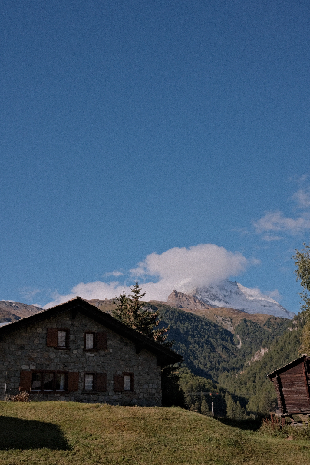 A stone hut with a peak-obscured Matterhorn in the distance