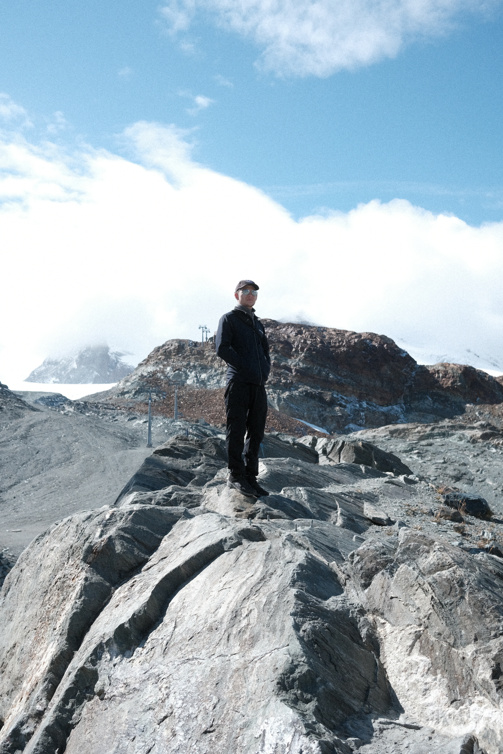 Tim climbing up a rocky outcrop with chairlifts in the distance