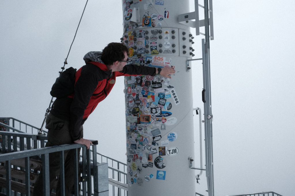 Nick placing a sticker on the pillar of stickers on the observation platform at Zermatt Glacier Paradise