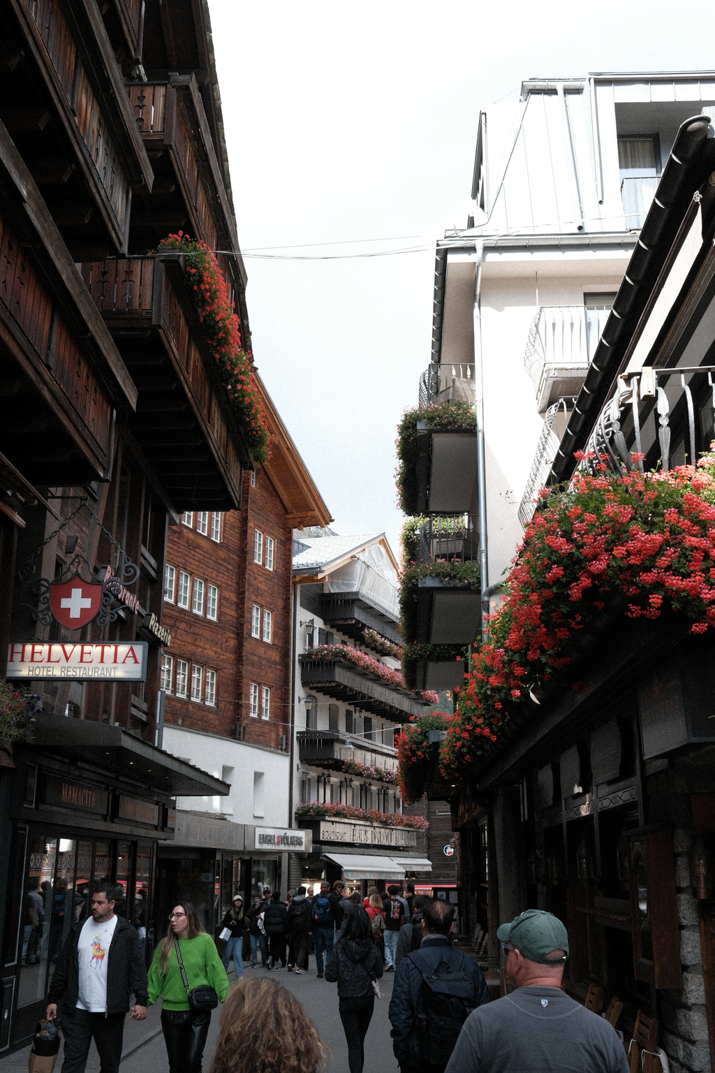 A narrow segment of Bahnofstrasse with a variety of flower-adorned balconies