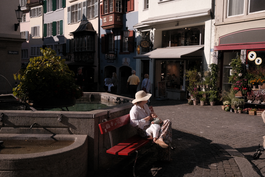 A woman and her baby sitting at the base of a fountain