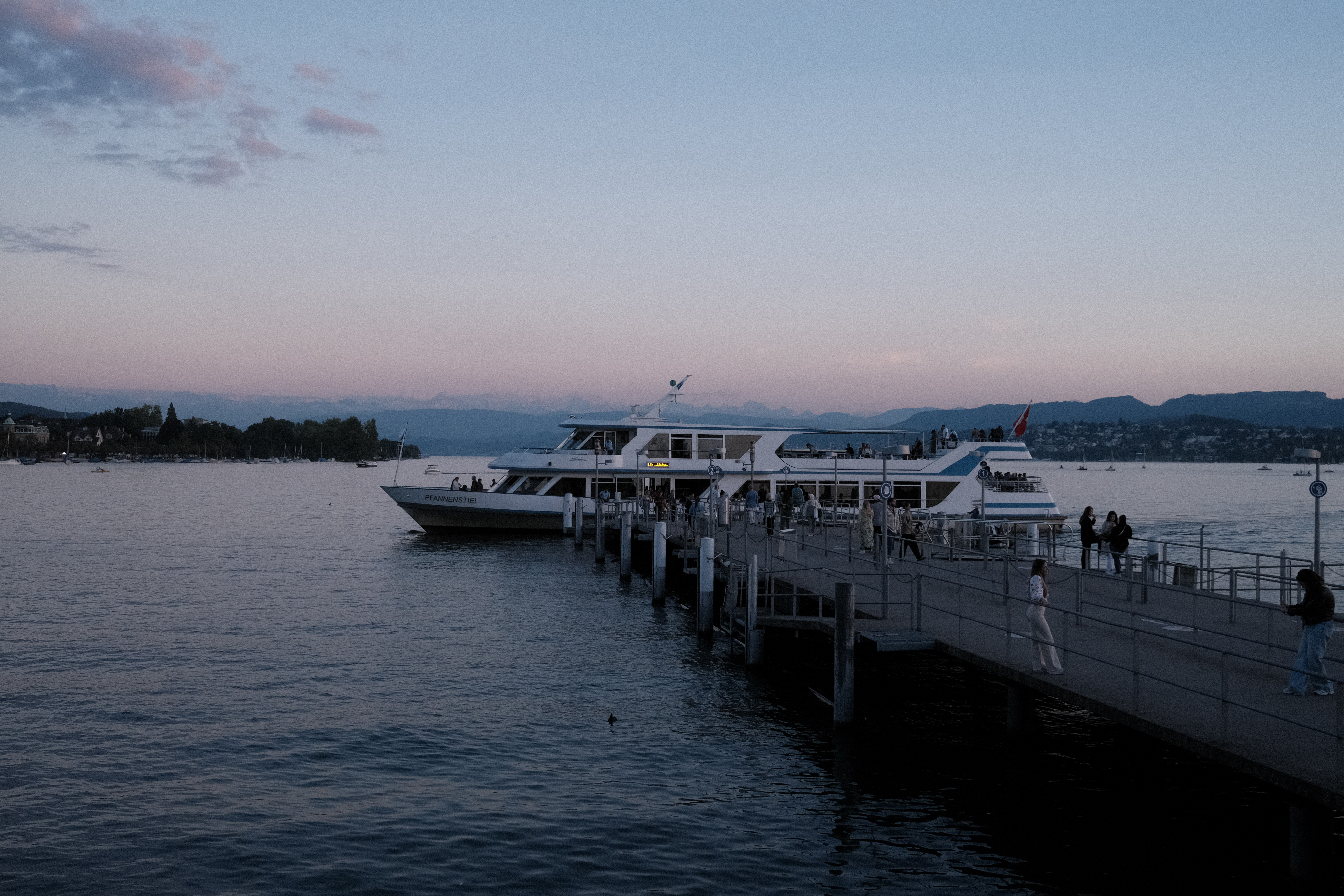 A lake-tour boat docking at Bürkliplatz at dusk