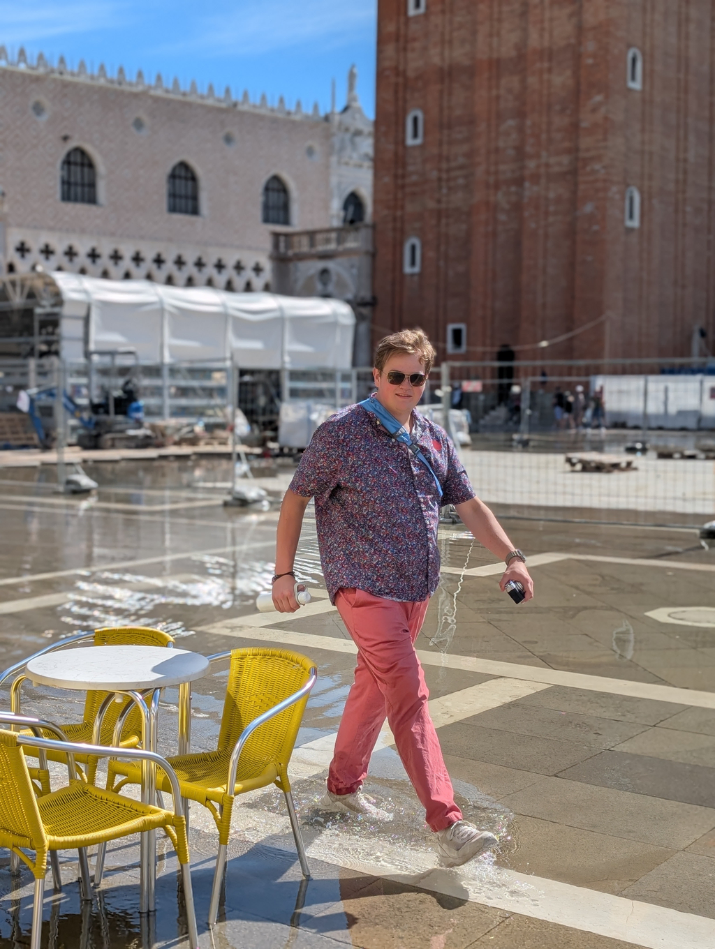 Sean walking through the Acqua Alta in San Marco's Square, holding his camera and water bottle