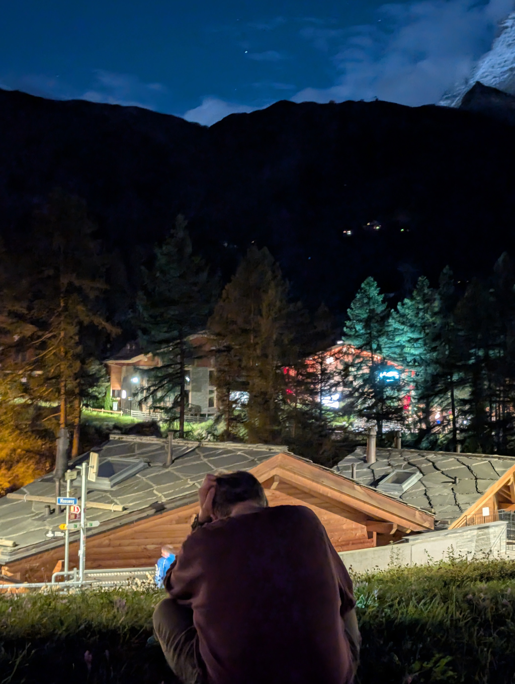 Sean sitting in a field, taking a long exposure picture of the Matterhorn